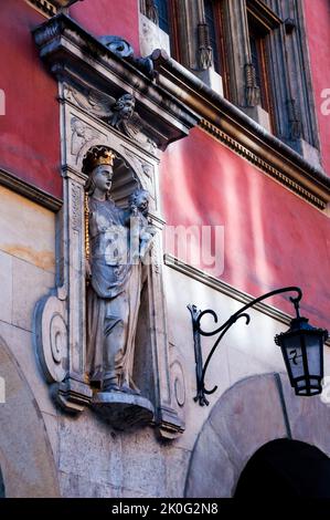 Architektonische Nische mit einer Statue von Maria, die ein Zepter hält und dem Jesuskind, das ein Kreuz hält, und einer alten Lampe mit der Hausnummer 7 in Krakau, Polen. Stockfoto