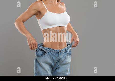 Erfolgreiche Ernährung. Frau in großen Jeans zeigt Ergebnisse ihrer Schlankheitskur Stockfoto