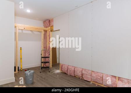 Nach der Installation von Wärme- und Schalldämmung für ein neues Zuhause wird die Trockenwand an den Wänden der Rahmenbalken verschraubt Stockfoto