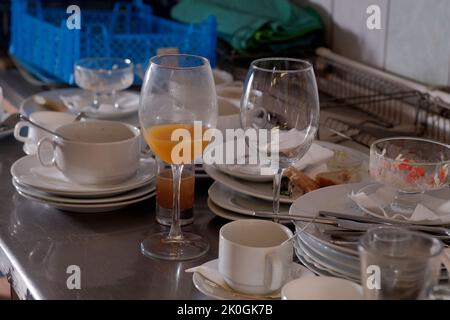 Schmutzige Teller und Gläser nach dem Essen in der Küche im Restaurant. Haufen oder Haufen von unsauberem Glas und Teller mit Frühstück oder Lunch-Tisch Stockfoto