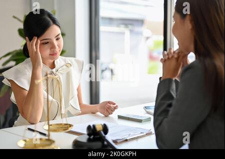 Eine gestresste asiatische Klientin konzentriert sich darauf, ihrer Anklage in ihrem Korruptionsfall zuzuhören. Rechtsberatung Konzept. Stockfoto