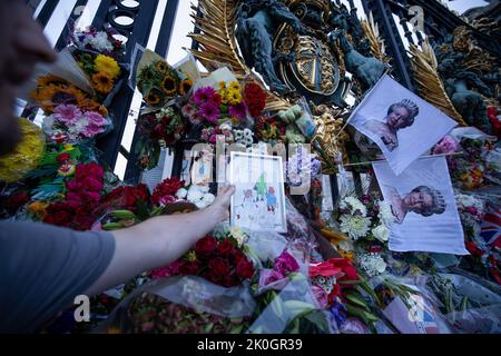 London, Großbritannien. 11. September 2022. Eine Person sah, wie sie eine Zeichnung von Königin Elizabeth II. Mit Paddington-Bär und Corgi auf die Blumen vor dem Buckingham Palace legte. Tausende Millionen Menschen aus der ganzen Welt kommen weiterhin zum Buckingham Palace, um Königin Elizabeth II. Zu Tribut zu zollen, die mehr als 70 Jahre auf ihrem Thron saß und am 8.. September 2022 starb. (Foto von Hesther Ng/SOPA Images/Sipa USA) Quelle: SIPA USA/Alamy Live News Stockfoto