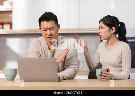 Wütende asiatische Frau, die ihren Mann mit einem Laptop anschrie Stockfoto