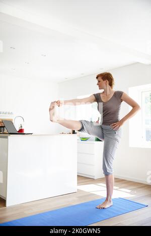 Die richtige Haltung. Eine attraktive Frau, die in ihrem Zuhause Yoga macht. Stockfoto