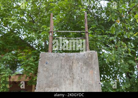 Die neu gebaute Betonsäule für das zukünftige Haus aus nächster Nähe - umgeben von grünen Bäumen Stockfoto