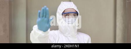 Person in Schutzanzug Maske und Brille stoppen Geste Stockfoto