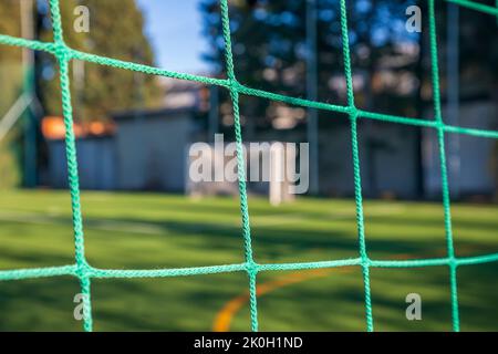 Grünes Fußballnetz auf einem Tor. Fußball-Netzknoten. Verschwommener Torpfosten im Hintergrund Stockfoto