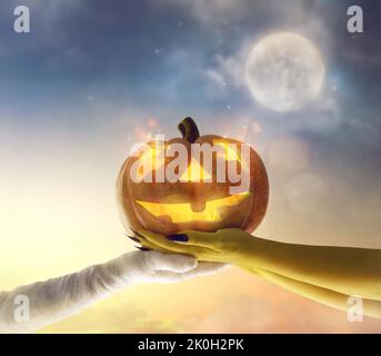 Halloween Kürbis in den Händen von Zombies und Mumien auf Mond Himmel Hintergrund. Stockfoto