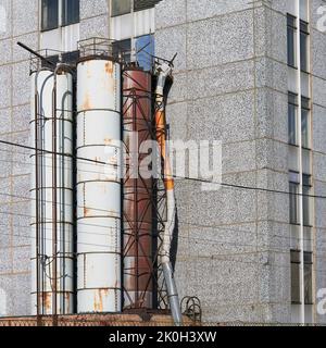 Industrierohre vom Ende des Gebäudes, rostige alte Rohre an der Seite der Fassade des Hauses Stockfoto