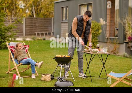 Fröhliche Tochter und ihr Vater mit der Grillparty Stockfoto