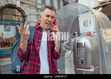 Mann im karierten Hemd, der am Straßentelefon sprach Stockfoto