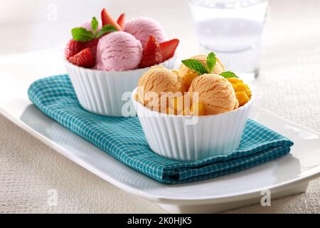 Zwei Schalen Eis mit Erdbeer- und Mangogeschmack, serviert mit Fruchtstücken Stockfoto