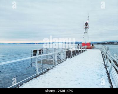 Die Menschen um den Ogden Breakwater Lighthouse im Winter in Victoria, Kanada Stockfoto