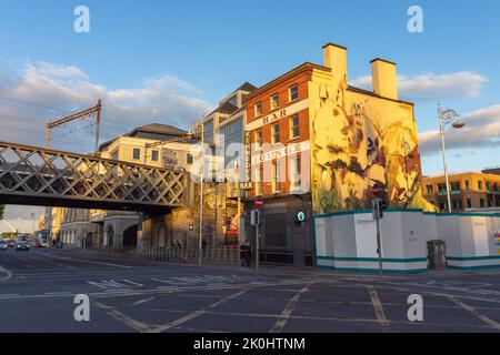 Das Workshop Gastropub Gebäude in Dublin, Irland unter Sonnenlicht mit Graffiti, einer Überführung und Verkehr Stockfoto