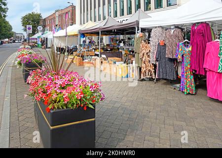 Farbenfrohe Sommerblumen in einer langen Reihe rechteckiger Blumenkästen an einem Tageskleider-Stand auf einem breiten Bürgersteig in Brentwood High Street Essex England Stockfoto