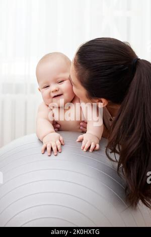 Mutter spielt mit ihrem kleinen Mädchen auf einem Fitnessball Stockfoto