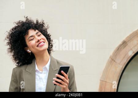 Glückliche Frau mit Ohrhörern lächelt und hört Musik Stockfoto