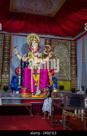 Ein Mädchen, das vor einem schönen Idol von Lord Ganesha in einem mandal in Mumbai für das verheißungsvolle indische Fest von Ganesh Chaturth betet Stockfoto