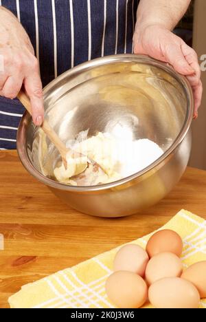 Nahaufnahme eines Womans Hände mischen Backen Mischung in einer Metallschale Stockfoto