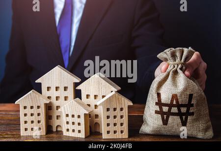 Ein Geschäftsmann legt einen südkoreanischen Geldbeutel in die Nähe der Häuser. Bauindustrie, Vermietung und Hoteltourismus. Investitionen in Immobilien Stockfoto