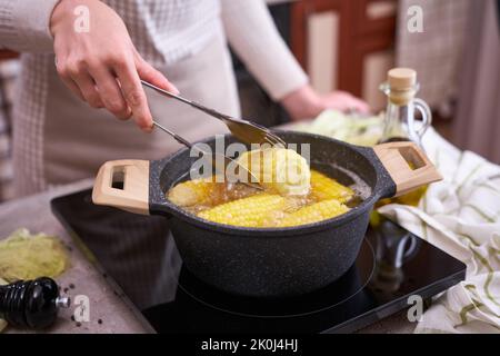 Kochen Maiskolben in einem Topf mit kochendem Wasser mit Blasen Stockfoto