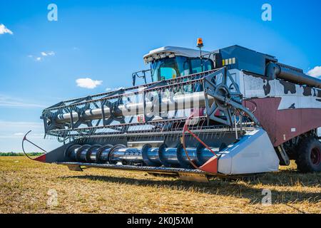 Landwirtschaftliche Maschine zum Mähen von Weizen und anderen Kulturen während der Ernte. Mähdrescher auf einem gemähten Weizenfeld Stockfoto