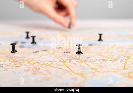 Frau, die auf der Karte den Stift drückt. Routenplanung, Veranstaltungskalender. Weibliche Markierung Reise Reiseroute mit Stecknadeln. Hochwertige Fotos Stockfoto