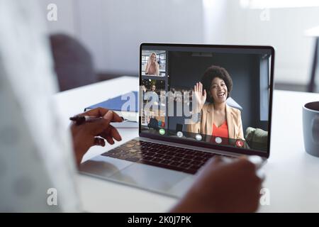 Hände einer afroamerikanischen Frau, die mit verschiedenen Kollegen einen Videoanruf auf einem Laptop führt und auf dem Bildschirm winkt. Geschäftskommunikation, Remote arbeiten und Zahlen Stockfoto