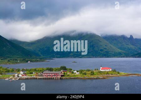 Blick auf den Austnesfjorden mit der Sildpollnes Kirche auf die bewölkten Berge, Lofoten, Norwegen Stockfoto