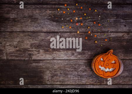 Handbemalter Lebkuchen gruselig Halloween alte Jack-o-Laterne Kürbis mit farbigen Streuseln auf Holzhintergrund. Draufsicht. Flach liegend. Speicherplatz kopieren Stockfoto