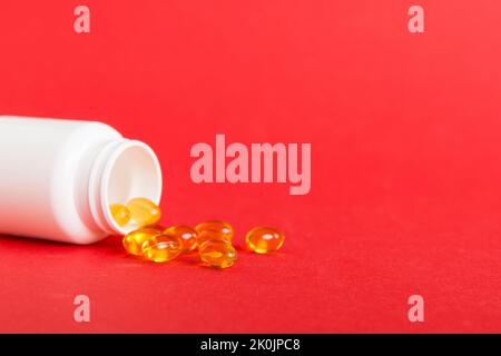 Weiche Geltabletten mit Omega-3-Öl, das aus der Pillenflasche aus der Nähe verschüttet wird. Gelkapseln Flasche weiße Oberfläche. Omega 3, Multivitamine, Kalzium, Antibiotika Stockfoto