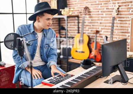 Junger nicht-binärer Musiker, der Klavier-Keyboard im Musikstudio spielt Stockfoto