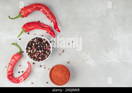 Draufsicht auf Chilischote und rote, schwarze, weiße Paprika und Paprikapulver. Mit Kopierbereich. Stockfoto
