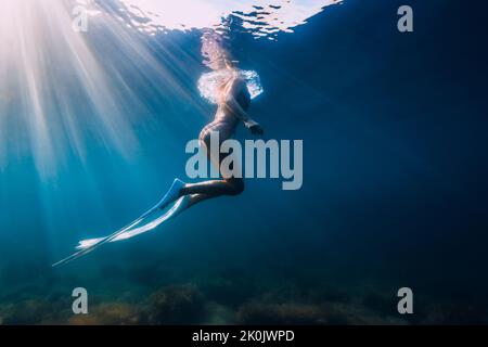 07. August 2021. Varna, Bulgarien. Frau mit freitauchende Flossen im Ozean mit Sonnenlicht. Junge Frau gleitet unter Wasser. Stockfoto