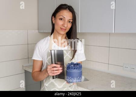 Eine Konditorin kocht einen Kuchen auf einem Tisch in der Küche in einer Konditorei. Stockfoto
