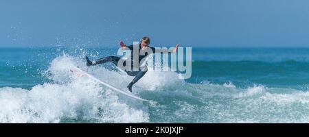 Ein Panoramabild von spektakulärer Surfing-Action, während ein Surfer eine Welle im Fistral in Newquay in Cornwall in Großbritannien reitet. Stockfoto