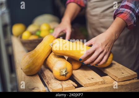 Frau arbeitet im Obst- und Gemüseladen. Sie stapelt Waren im Schaufenster. Stockfoto