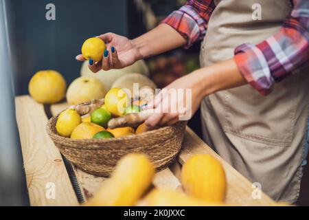 Frau arbeitet im Obst- und Gemüseladen. Sie stapelt Waren im Schaufenster. Stockfoto