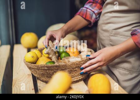 Frau arbeitet im Obst- und Gemüseladen. Sie stapelt Waren im Schaufenster. Stockfoto