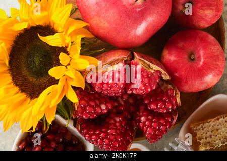 Rosh Hashanah. Reife Granatapfel, Apfel, Honig und Sonnenblume, gelbe Blüten auf rustikalem grauen Hintergrund. Komposition mit Symbolen Herbst jüdischen Rosch hat Stockfoto