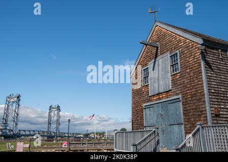 Portsmouth, NH, USA, 7. September 2022: Das historische Sheafe Warehouse im Prescott Park mit der modernen Memorial Bridge im Hintergrund. Stockfoto