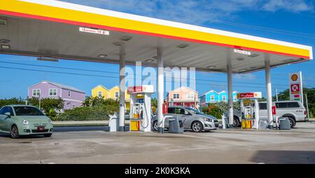 Key West, FL, USA, 28. Dezember 2016: Autos füllen sich an der Tankstelle mit bunten Häusern im Hintergrund. Stockfoto