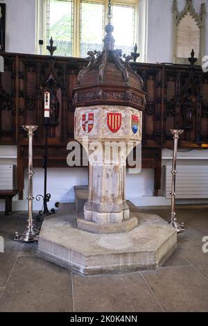 Das aus Stein geschnitzte Taufbecken mit geschnitzter Holzkappe. In der Little St Mary's Kirche in Cambridge, England, Großbritannien. Stockfoto