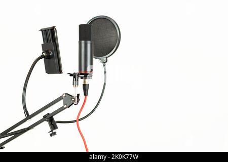 Modernes professionelles schwarzes Mikrofon auf dem Ständer mit Drähten und rundem POP-Filter, isoliert auf weißem Hintergrund, in einem modernen Lichtstudio Stockfoto