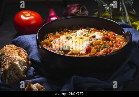 Appetitliches traditionelles spanisches Gericht aus Ei und verschiedenen Gemüsesorten, das in einer Schüssel auf dem Tisch serviert wird Stockfoto