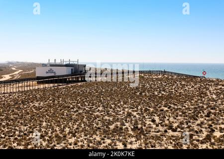 Touristen, die auf dem Holzsteg zum Strand und über das Naturschutzgebiet Parque Natural da Ria Formosa in der Nähe von Quinta do Lago gehen Stockfoto