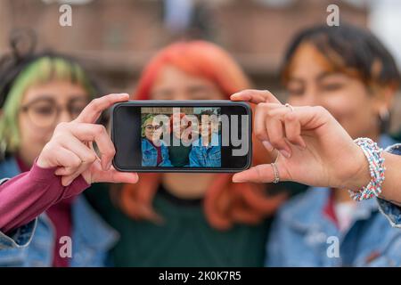 Verschwommene multirassische Freundinnen, die Selfie-Fotos auf dem Mobiltelefon machen, während sie sich in der Stadt Cusco ausruhen Stockfoto