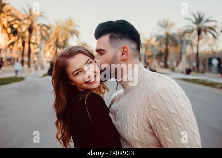 Junger Mann küsst eine attraktive Frau auf die Wange in den Straßen von Barcelona, Spanien Stockfoto