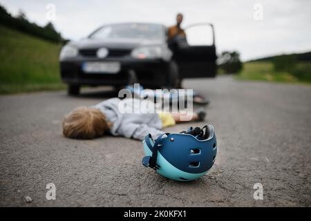 Kleiner Junge fiel vom Fahrrad und lag nach einem Autounfall noch auf der Straße. Stockfoto