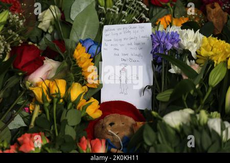 London, Großbritannien. 12. September 2022. Nach dem Tod von Queen Elizabeth II am Donnerstag legt ein Kind eine Karte mit Blumenschmuck im Green Park, in der Nähe des Buckingham Palace, London, auf. Bilddatum: Montag, 12. September 2022, London. Quelle: Isabel Infantes/Alamy Live News Stockfoto